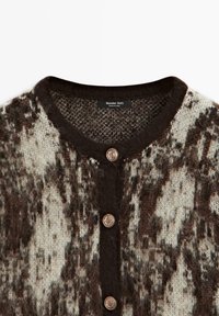 Cardigan en maille marron et blanc avec encolure ronde, trois boutons décoratifs dorés et étiquette de la marque Massimo Dutti à l'intérieur du col.