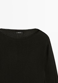 Pull noir en maille avec encolure ronde et couture d'épaule courte, montrant la partie supérieure de la poitrine et l'étiquette de la marque à l’intérieur du col.