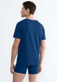 T-shirt in cotone blu navy con collo a giro, maniche corte e vestibilità rilassata, abbinato a pantaloni boxer blu navy coordinati.