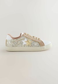 Spilgti sporta apavi ar baltu ādas purngalu un mēli, zelta un bēša akcentiem, ar mirdzošu augšdaļu un zvaigžņu rakstiem sānos.