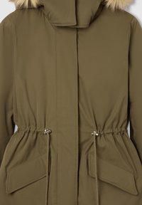 Oliwkowa parka z futrzanym kapturem, elastycznym pasem i dwiema dużymi kieszeniami z przodu. Gładka faktura z marszczeniami i solidnymi zapięciami.