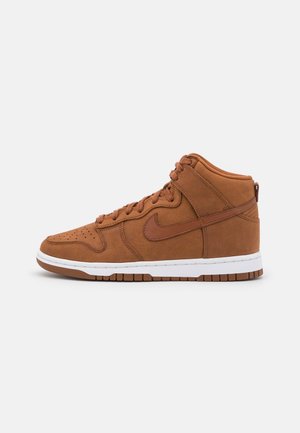 Baskets montantes Nike marron avec texture en daim, bout perforé, logo swoosh marron, semelle intermédiaire blanche et semelle extérieure en caoutchouc marron.
