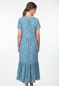 Maxikleid mit Blumenmuster in Blau, kurzen Ärmeln, gerafftem Bund und einem gestuften Rüschensaum. Das Material wirkt leicht und strukturiert.