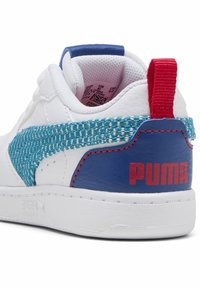 Sneaker bianco con accenti blu testurizzati e turchese intrecciato, colletto imbottito, linguetta rossa sul tallone e logo "PUMA" rosso sul lato.