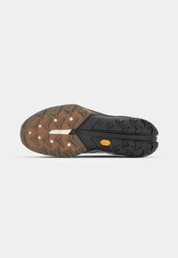 Semelle en caoutchouc noire et marron, avec un motif de grip texturé, arborant un logo Vibram et une combinaison de sections surélevées et planes.