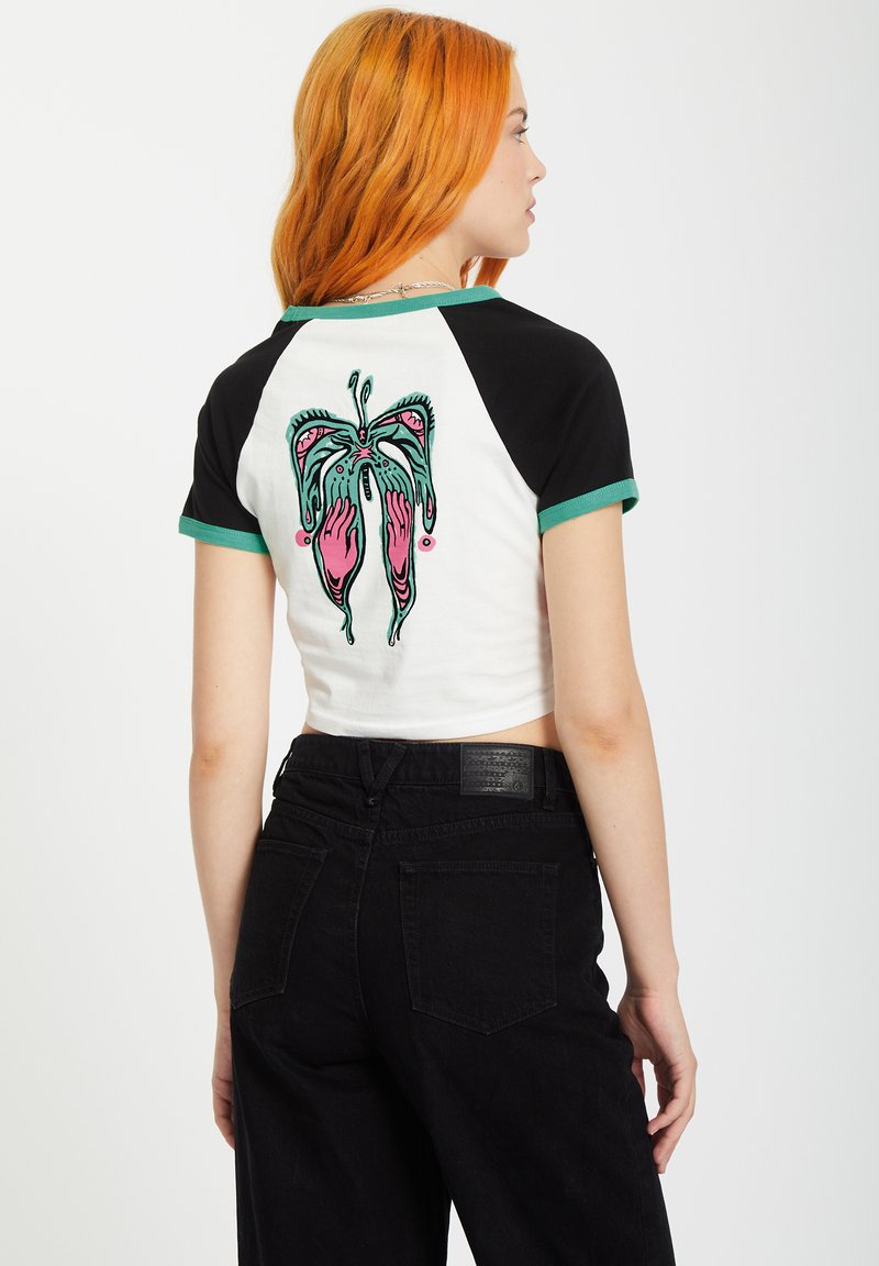 Weißes Crop-Top mit schwarzen Ärmeln und grünem Saum. Auf der Rückseite befindet sich ein farbenfrohes grafisches Design von Händen und einem Schmetterling.