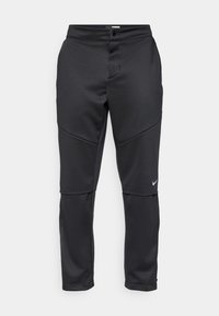 Black athletic pants with a smooth texture, featuring panel designs and a small white Nike logo on the left leg.