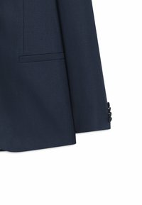 Manche de veste de costume bleu marine foncé avec trois boutons noirs et une poche à fente horizontale sur le côté inférieur.