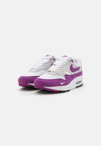 Bele in vijolične Nike Air Max superge z zgornjim delom iz semiša in mreže, okrogli nos, vezalni sistem in zračno blazinico v podplatu.