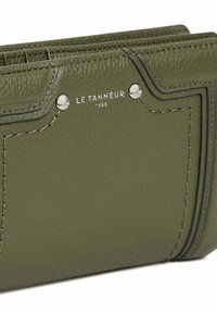 Portafoglio in pelle verde con cuciture visibili, logo impresso e dettagli in metallo. Presenta una finitura texturizzata e un design strutturato.