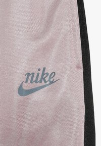 Spodenki sportowe Nike o różowej teksturowanej powierzchni i czarnych akcentach, z niebieskim logo po boku.