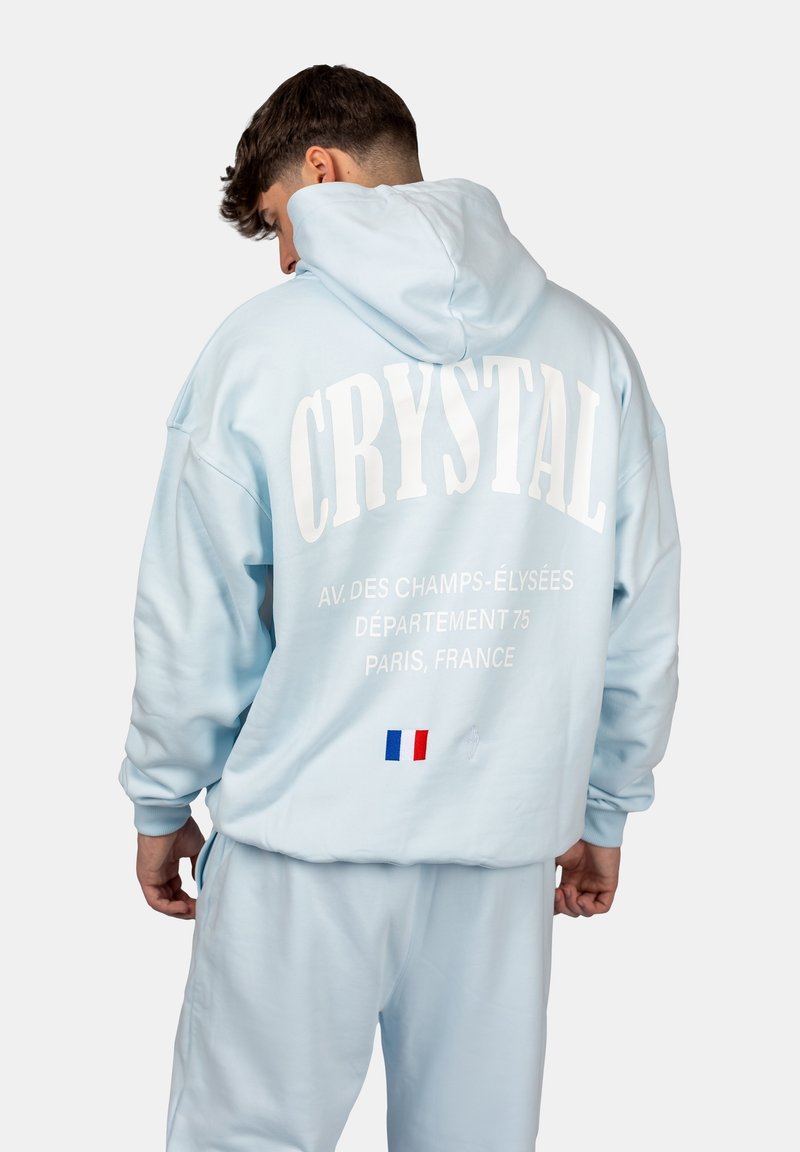Hellblaues Hoodie mit weißem "CRYSTAL"-Text und Paris-Standortdruck auf der Rückseite. Verfügt über eine Kängurutasche und gerippte Bündchen.