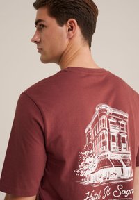 Marmoreret bomulds t-shirt med et hvidt konturdesign af en bygning på ryggen, med korte ærmer og rund halsudskæring.