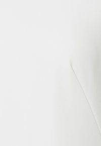 Vitt textil med en slät textur, med en minimalistisk design och subtila sömmar. Inga mönster eller hårdvara synliga.