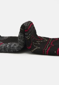 Calcetines de punto con un diseño estampado en tonos rojos, grises y verdes sobre un fondo negro. Textura suave, doblados para mostrar.