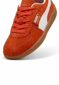Puma Palermo jooksujalatsid oranžis nahas, valgete aktsentidega ja tekstuurse kummitaldaga. Paelad sobivad ülaosaga ja tagavad kindla istuvuse.