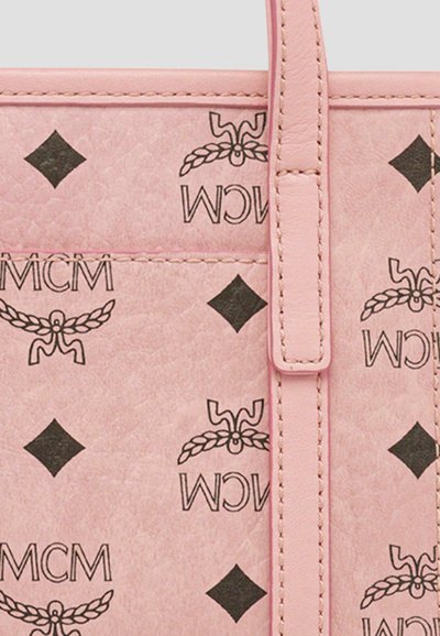 Pink leather tote bag featuring black MCM logo patterns and diamond shapes, with stitched accents and a flat top handle.