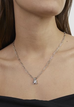 Sølvkæde med forlænsforbundne led og tre vedhæng, to klare krystaller og en uregelmæssig form, med en poleret finish.