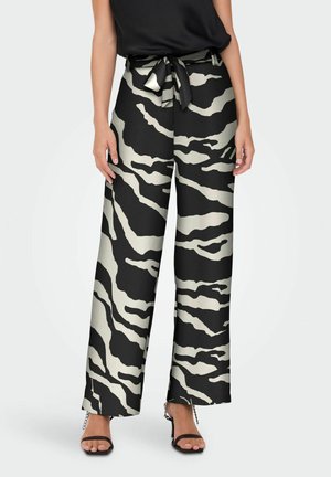 Black and cream zebra-print wide-leg trousers with a matching tie belt; smooth fabric; tailored fit; paired with black strappy heels.