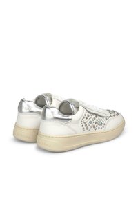 Białe sneakersy z chropowatą skórzaną cholewką, srebrnymi akcentami na pięcie i dekoracyjnymi ćwiekami po bokach. Jasnobeżowa gumowa podeszwa.