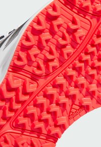 Red rubber shoe sole featuring a textured zigzag pattern, with a white upper and black accents. Adidas logo visible in the corner.