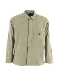 Light olive green long-sleeve button-up shirt in corduroy fabric, featuring a chest pocket with a small logo badge and a collared neckline.