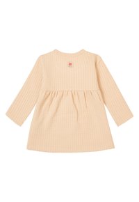 Langarm jurk van zacht perzikkleurig stof met een gestructureerd wafelpatroon, voorzien van een geraffineerde taille en een klein geborduurd logo aan de achterkant.