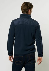 Pullover in pile blu navy con collo alto, dotato di un pannello in tessuto liscio a contrasto sulle spalle. Texture sottile, maniche lunghe e vestibilità rilassata.