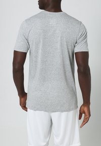 Camiseta gris de cuello redondo hecha de mezcla de algodón, con mangas cortas y un dobladillo recto de textura suave. Diseño minimalista.