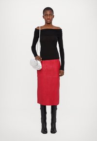 Zwarte off-shoulder top, rode leren rok, zwarte kniehoge laarzen en een zilveren tas met een geplooid ontwerp. Eenvoudige, gestructureerde silhouet.