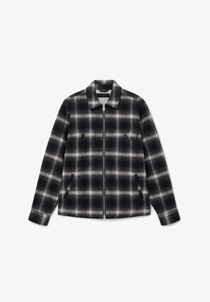 Chaqueta de cuadros en blanco y negro con cremallera, un cuello, dos bolsillos frontales y bolsillos en el pecho con botones, que presenta una tela suave y texturizada.