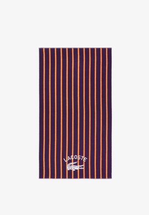 Lila Handtuch mit vertikalen orange-weißen Streifen und einem weißen Lacoste-Logo samt Krokodil in der unteren Mitte.