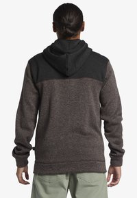 Hooded sweatshirt featuring a dark gray top panel, textured brown body, elastic cuffs, and a drawstring hood. Subtle stitching detail at the hem.