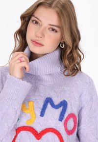 Lavendelfarbenes Strickpullover mit Rollkragen, ausgestattet mit bunten Filzbuchstaben und einem Herz-Graphic. Zeigt gerippte Bündchen und einen strukturierten Stoff.