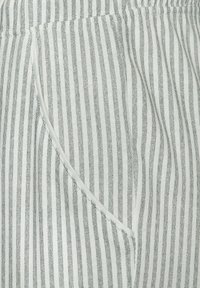 Grau- und weiß gestreifter Stoff mit einer weichen Textur, versehen mit einer Tasche mit einem kontrastierenden weißen Rand entlang der Kante.