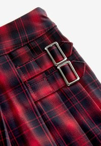 Red and navy plaid fabric featuring a smooth texture, with two rectangular silver buckles and visible stitching details.