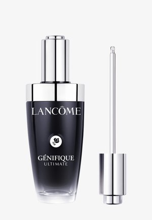 Flacon du sérum Lancôme Génifique Ultimate avec le bouchon compte-gouttes argenté retiré, montrant un applicateur fin à côté du contenant noir et argenté.