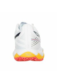 Scarpa sportiva bianca con accenti neri e grigi, suola gialla e rossa, e branding "Mizuno Energy" sul tallone, mostrata dalla vista posteriore.