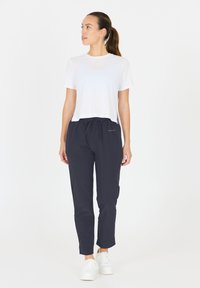Vit kortärmad t-shirt som matchas med mörkt marinblå träningbyxor. Byxorna har dragsko i midjan och åtsittande cuffs; bärs med vita sneakers.