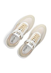 Beige und cremefarbene Sneakers mit einem Mesh-Obermaterial, weißen Schnürsenkeln und einem reflektierenden Akzent an der Seite. Verfügen über eine strukturierte Sohle und Logo-Details.