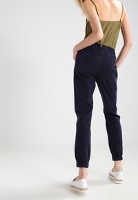 Joggers navy à taille élastique avec jambes fuselées, dotés de poches latérales. Assortis à un haut vert olive ajusté et des espadrilles légères.