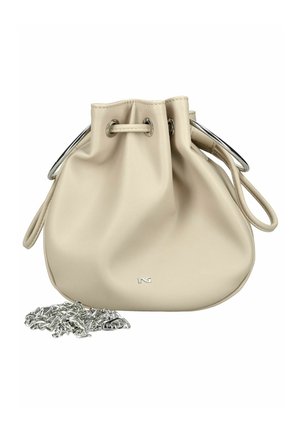 Beżowa skórzana torebka na sznurek z metalowymi srebrnymi przelotkami oraz odpinanym srebrnym łańcuszkiem umieszczona obok niej.