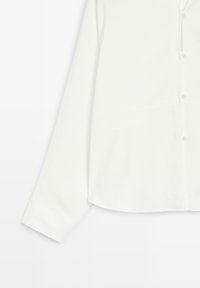 Hvid skjorte med knapper og lange ærmer, der har en glat tekstur, afrundet kant og diskrete syninger på fronten og ærmerne.