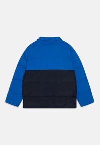 Padded jacket in bright blue and navy, featuring a collar, long sleeves, and a horizontal color-block design with prominent quilted texture.