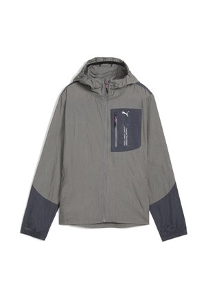 Chaqueta ligera en gris con acentos en marino. Cuenta con capucha, puños elásticos y tejido texturizado. Combinada con pantalones cortos grises y forro rosa.