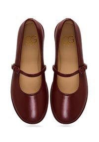 Zapatos Mary Jane de cuero burdeos con punta redondeada, una correa en el empeine y un acabado suave y brillante. El interior cuenta con un forro color tostado.