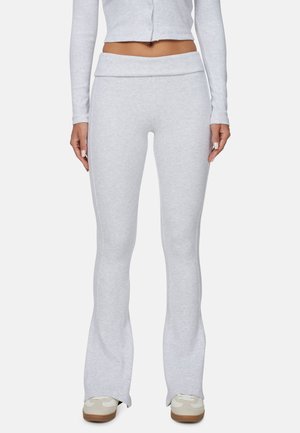Lichtgrijze, uitlopende sweatpants van zacht textuur met een brede tailleband, aangevuld met een bijpassend cropped langemouwen top en casual sneakers.
