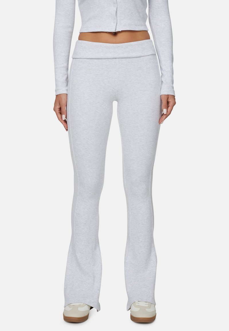 Jasnoszare, dzwonowate dresy z miękkiego materiału o teksturowanej powierzchni z szerokim paskiem, uzupełnione dopasowanym krótkim swetrem z długim rękawem i sportowymi butami.