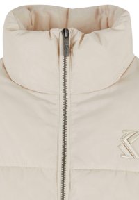 Lys beige pufferjakke med høy krage, sølvfarget glidelås og brodert logo på høyre side. Har glatt, teksturert stoff.