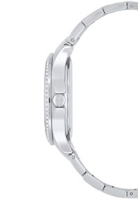 Sølvfarvet ur med et elegant design, metalarmbånd, struktureret kasse og en række små krystaller langs bezellet. Vist fra siden.